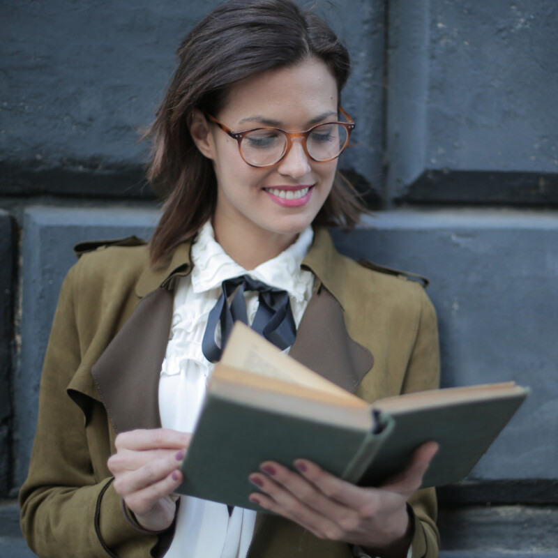 Group leader of a study holiday smiling while reading a book and wearing glasses