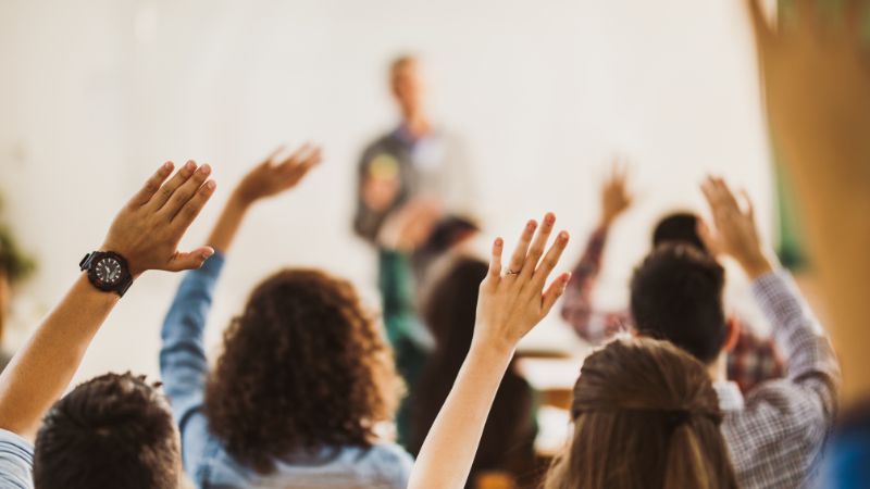 studenti con amano alzata per partecipare
