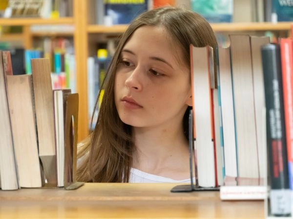 child browsing through books in the library looking through the shelf