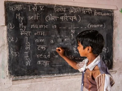 boy writing in hindi on blackboard