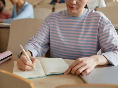 young student studying in a classroom with a notebook and pen