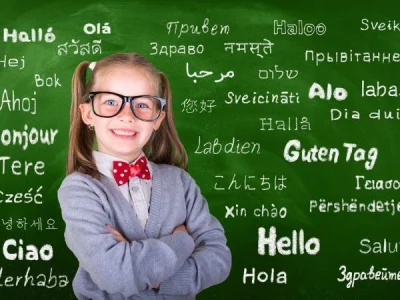 little girl stood beside language names written in chalk